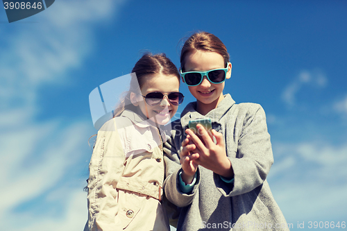 Image of happy girls with smartphone taking selfie outdoors