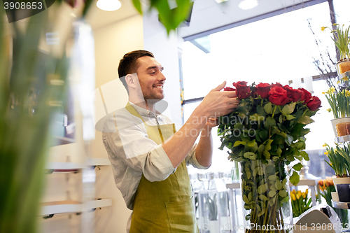 Image of smiling florist man with roses at flower shop