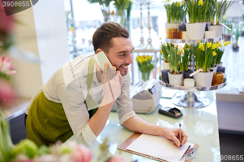 Image of man with smartphone making notes at flower shop