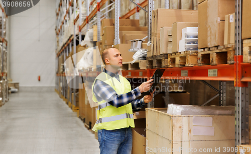 Image of man with clipboard in safety vest at warehouse