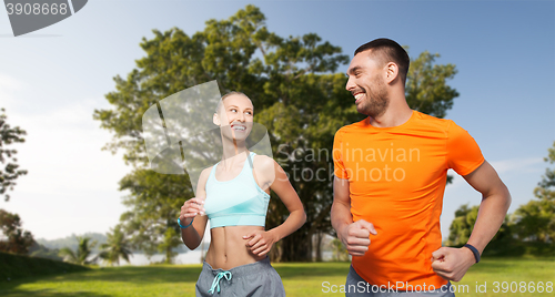 Image of smiling couple running over summer park background