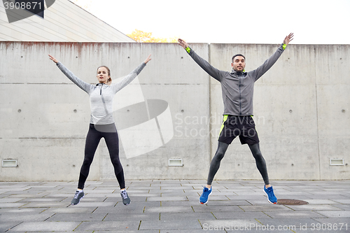 Image of happy man and woman jumping outdoors