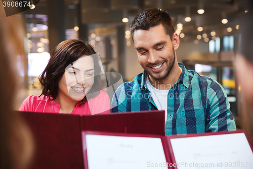 Image of smiling couple with friends and menu at restaurant