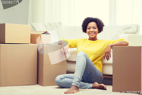 Image of happy african woman with cardboard boxes at home