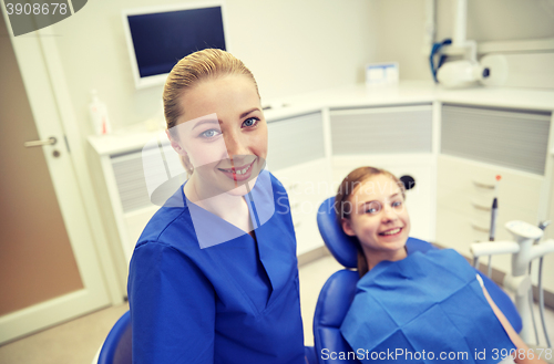 Image of happy female dentist with patient girl at clinic