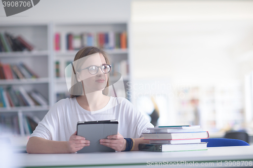 Image of female student study in school library, using tablet