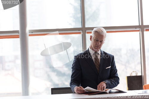 Image of senior business man reading magazine