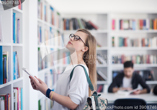 Image of famale student selecting book to read in library