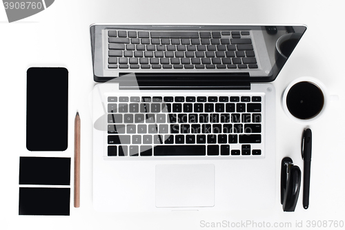 Image of Business laptop, phone and a coffee on the white table 