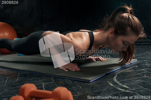 Image of Beautiful slim brunette doing some push ups a the gym