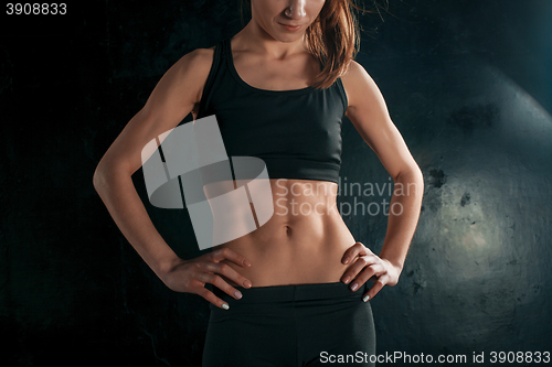 Image of Muscular young woman athlete on black