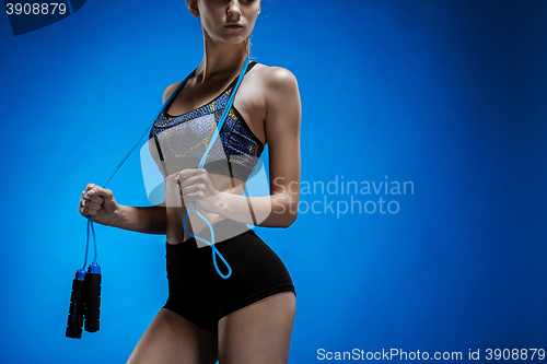Image of Muscular young woman athlete with a skipping rope on blue