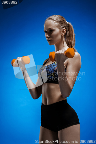 Image of Sporty woman doing aerobic exercise with red dumbbells