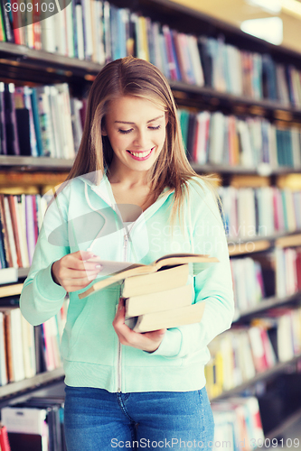 Image of happy student girl or woman with book in library