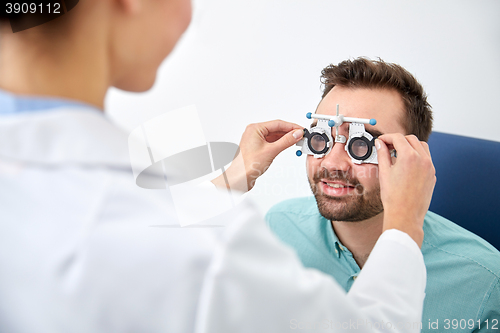 Image of optician with trial frame and patient at clinic