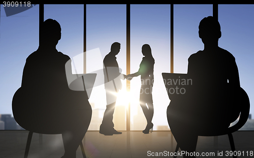 Image of business partners silhouettes shaking hands