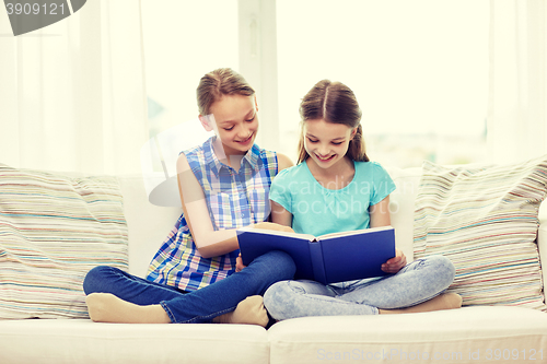 Image of two happy girls reading book at home