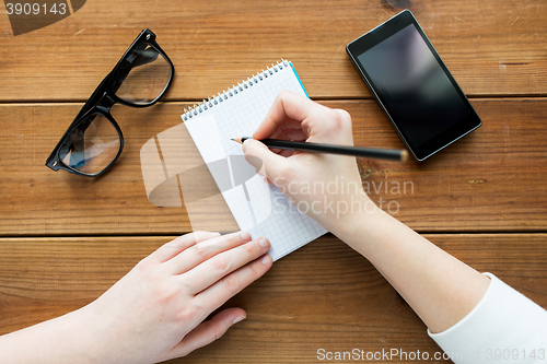 Image of close up of woman or student writing to notepad