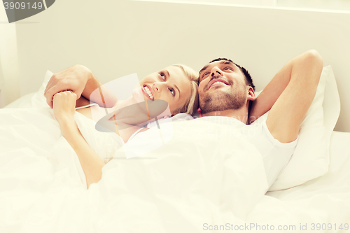 Image of happy couple lying in bed at home