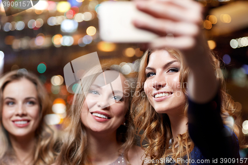 Image of women with smartphone taking selfie at night club