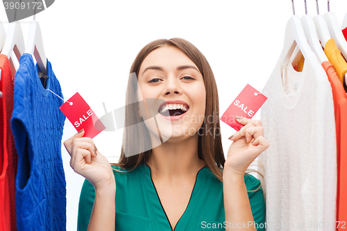 Image of happy woman with sale tags on clothes at wardrobe