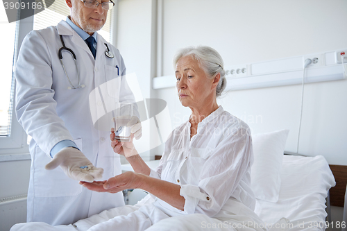 Image of doctor giving medicine to senior woman at hospital