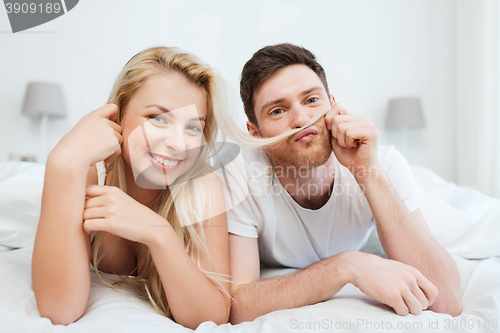 Image of happy couple lying in bed at home