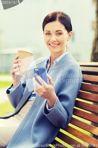 Image of smiling woman with coffee and smartphone