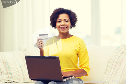 Image of happy african woman with laptop and credit card