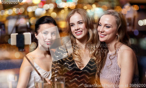 Image of women with smartphone taking selfie at night club