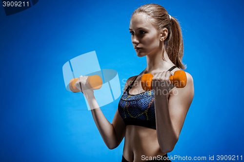 Image of Sporty woman doing aerobic exercise with red dumbbells