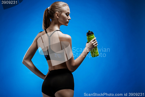 Image of Muscular young woman athlete with a water on blue