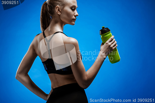 Image of Muscular young woman athlete with a water on blue