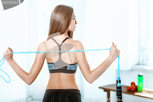 Image of Muscular young woman athlete with a skipping rope on white