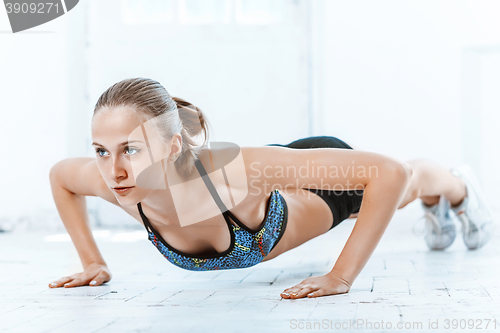 Image of Beautiful slim brunette doing some push ups a the gym