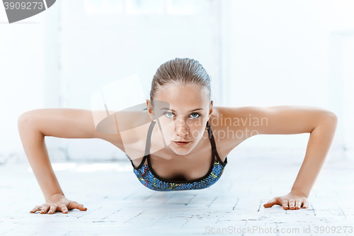 Image of Beautiful slim brunette doing some push ups a the gym