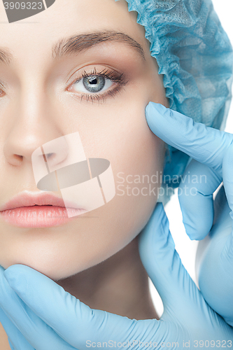 Image of Plastic surgery concept. Doctor hands in gloves touching woman face