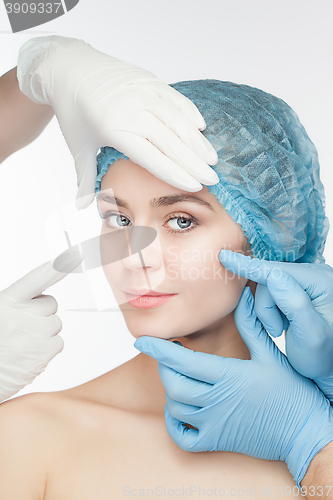Image of Plastic surgery concept. Doctor hands in gloves touching the beautiful woman face on white