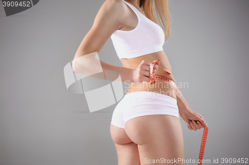 Image of Woman holding meter measuring perfect shape of her beautiful body