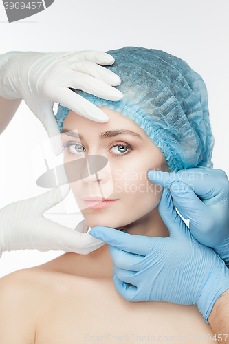 Image of Plastic surgery concept. Doctor hands in gloves touching the beautiful woman face on white