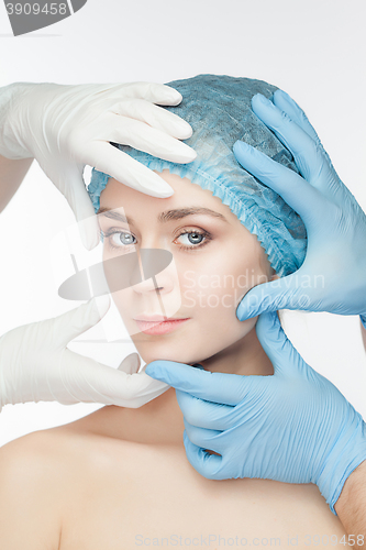 Image of Plastic surgery concept. Doctor hands in gloves touching the beautiful woman face on white