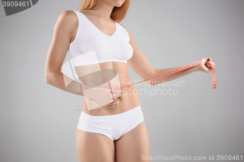 Image of Woman holding meter measuring perfect shape of her beautiful body