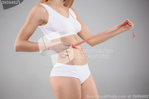 Image of Woman holding meter measuring perfect shape of her beautiful body