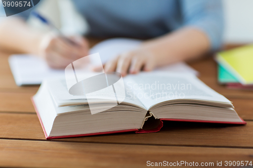 Image of close up of student with book and notebook at home