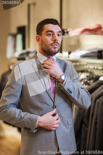 Image of young man trying suit on in clothing store