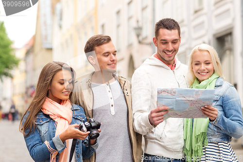 Image of group of smiling friends with map and photocamera