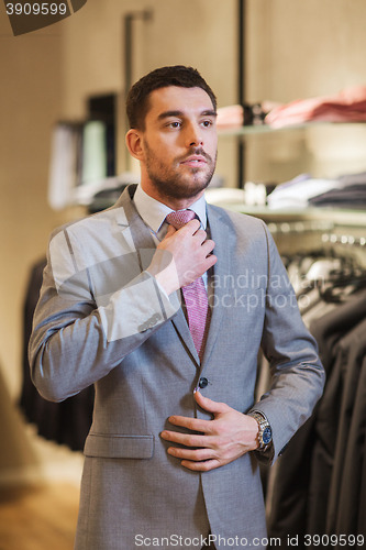 Image of young man trying suit on in clothing store