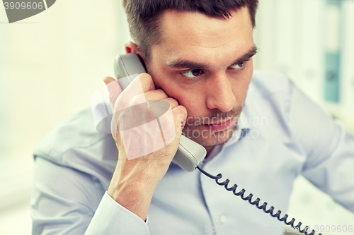 Image of face of businessman calling on phone in office