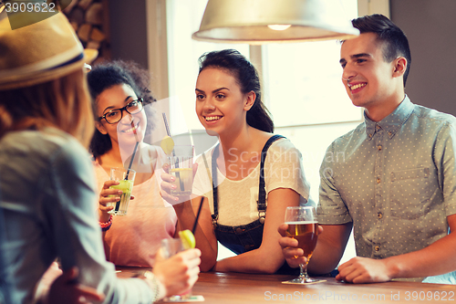 Image of happy friends drinking beer and cocktails at bar