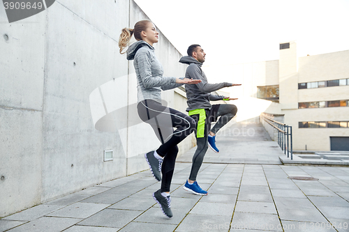 Image of happy man and woman jumping outdoors